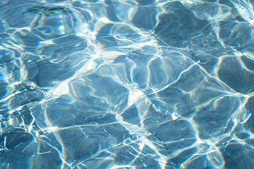 Clearly blue water surface which is reflected with sunlight. Abstract texture photo, close-up.
