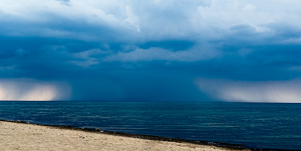 Thunder clouds over open  water with large descending storm front