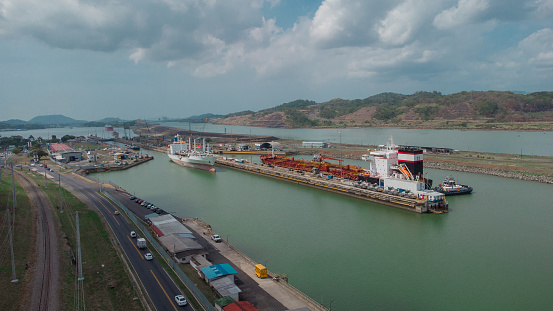 Boat passing Pedro Miguel locks in Panama, famous channel shortcut in central America. Visible ships and channels with locks. Drone view on a cloudy but sunny day in spring.