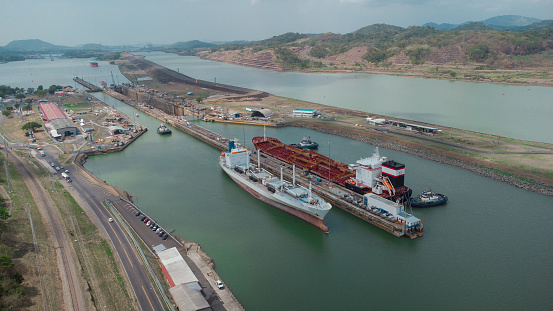 Boat passing Pedro Miguel locks in Panama, famous channel shortcut in central America. Visible ships and channels with locks. Drone view on a cloudy but sunny day in spring.