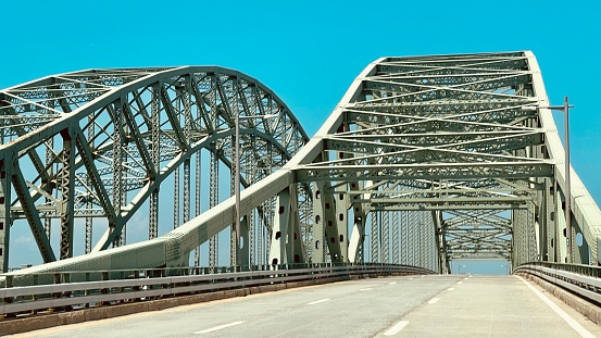 view of an old metal bridge, shaded ground and blue sky