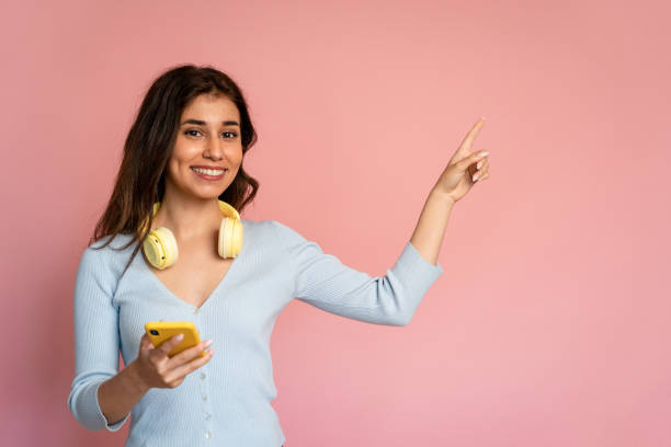 istock Woman pointing to the side while holding a cell phone. 1545812838