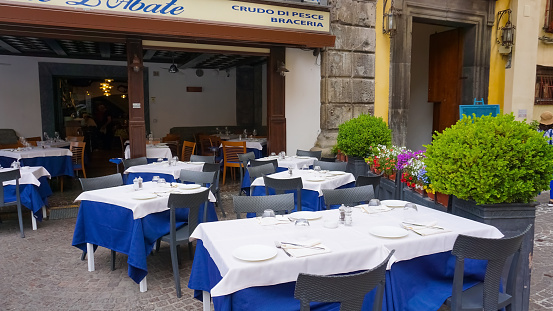 Sorrento, Italy - May 27, 2023: Typical Sorrento restaurant Ristorante Pizzeria L'Abate based on the sea with empty tables.