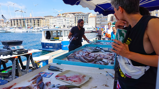 Marseille, France - May 29, 2023: French fisherman selling fresh fish at Vieux Port in Marseille, France. Marseille is France's largest city on the Mediterranean coast and the largest commercial port.