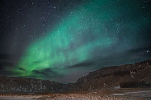 A breathtaking view of the aurora borealis in the night sky above Reykjavik, Iceland, with stars twinkling in the background