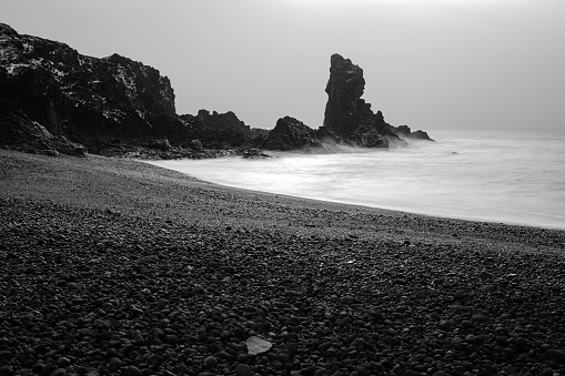 An idyllic beach scene in Reykjavik, Iceland featuring black sand and a foggy weather