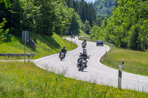 Tirol, Austria - June 25, 2023: Bikers and cars driving on a country road in the Alps