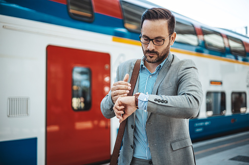 Anxious executive manager looking at his watch in train station. Business Commuter Checking Time. Worried businessman looking at his watch in train station.