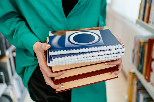 Close-up of a female student holding books in a student library at the university.