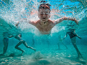 Child jumps underwater in the blue sea