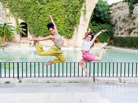 Photo with copy space of happy two women jumping happily on a park