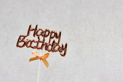 happy birthday text concept with ribbon isolated on gray background