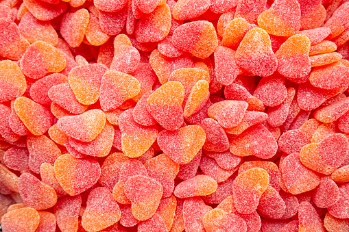 Background of red gummies in the form of hearts with a sugar coating.