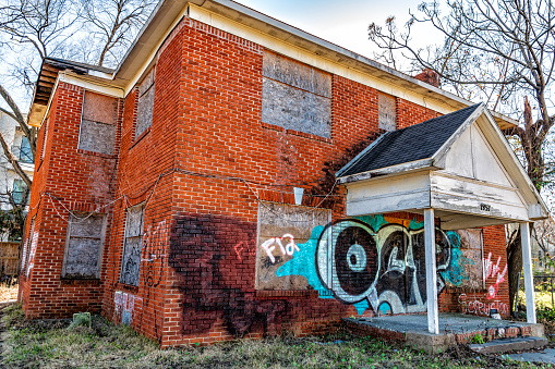 Houston, United States - January 8. 2023:  An abandoned and boarded up house along a main city street near downtown Houston, Texas as an example of urban blight.