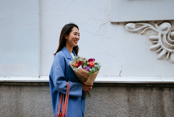 Beautiful Asian Woman Walking down the Street Carrying a Flower Bouquet stock photo