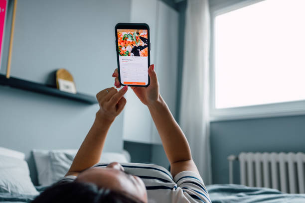 istock Anonymous Woman Lying on her Bed and Using a Smartphone to Order Something Online 1546278156