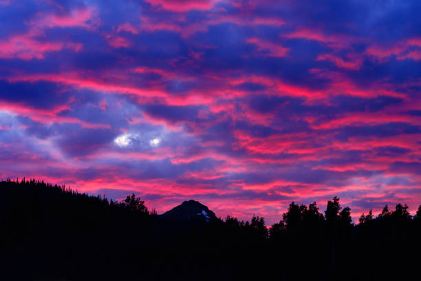 Dramatic Pink Clouds and Mountain Peak Scenic Summer Landscape - Alpenglow on upper clouds getting lit up from underneath. Classic mountain sunset landscape with copy space.