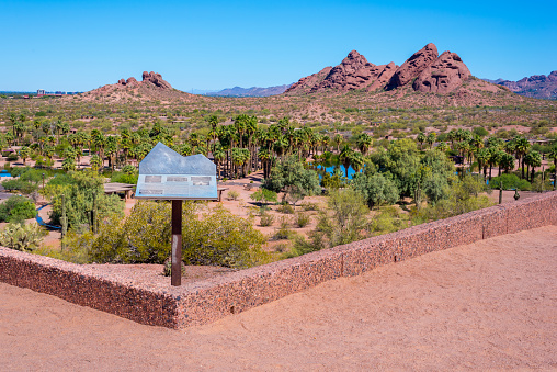 A pedestal displaying historical information about George Hunt, the first governor of Arizona, who is entombed at the site, overlooks Papago Park's ponds and red sandstone buttes.