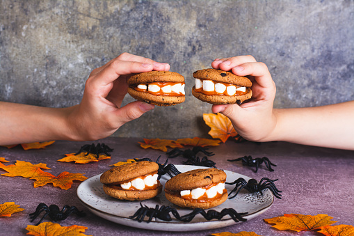 Halloween treats cookies with marshmallow teeth in children's hands
