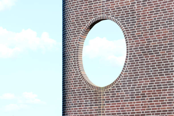 Brick wall with round window against blue sky background