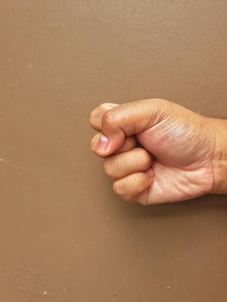 istock Hand giving clenched fist on brown background 1546586812