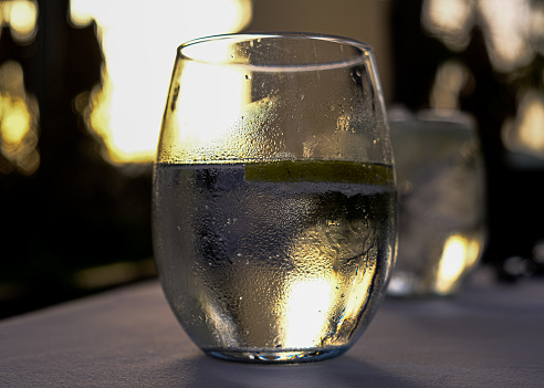 A glass of cold icy water in the lights of the golden hour