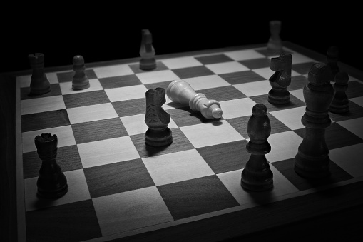 Chess board in black and white with the queen piece fallen down