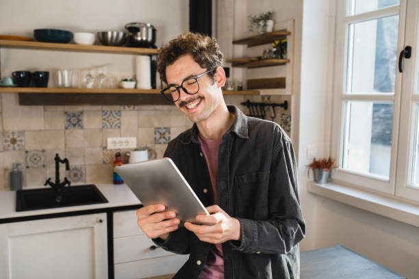 Young man watching something fun on his digital tablet Portrait of a young man relaxing at home and using a digital tablet man 30 years old stock pictures, royalty-free photos & images