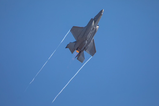 F22 Raptor fighter plane with afterburners and white wingtip vortexes