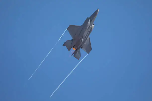 F22 Raptor fighter plane with afterburners and white wingtip vortexes