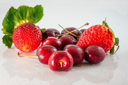 Several fresh ripe cherries and strawberries close up