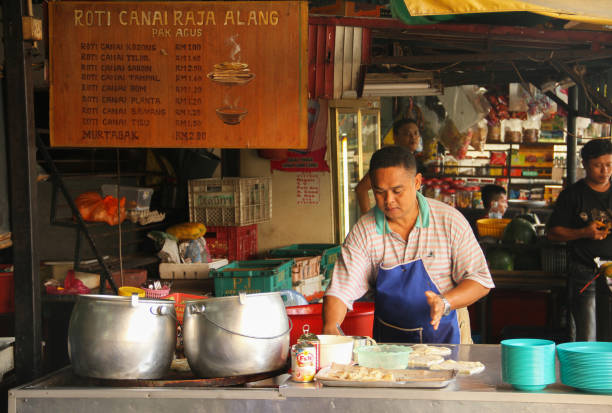 A man selling roti canai or roti prata, a traditional Indian flat bread dish with various curry and dahl sauces served mostly at breakfast time from a small warung in the Chow Kit Road Market of Kuala Lumpur, Malaysia. July 18, 2010 - Kuala Lumpur, Malaysia.
A man selling roti canai or roti prata, a traditional Indian flat bread dish with various curry and dahl sauces served mostly at breakfast time from a small warung in the Chow Kit Road Market of Kuala Lumpur, Malaysia. roti canai stock pictures, royalty-free photos & images