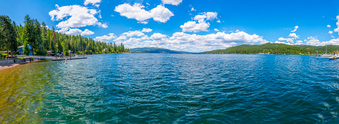 Panoramic view from the public beach of waterfront homes, marina and the mountains surrounding Carlin Bay, one of the bays on Lake Coeur d'Alene, in Coeur d'Alene, Idaho, in the North Idaho Panhandle. Carline Bay is located on the eastern shore of Coeur d'Alene Lake in the Bitterroot Range of the Rocky Mountains.