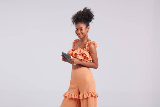 istock Stylish Reader: Black Girl in Orange Shirt Posing with Book in Studio 1547166095