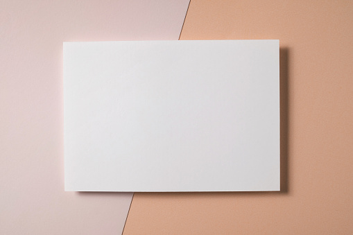 White blank greeting or invitation card mockup on beige paper background. Mock up presentation. Flat lay, top view with copy space. Minimal modern style.