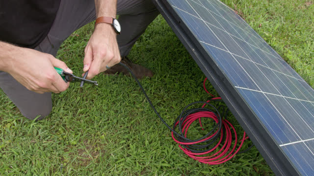 Man Stripping a Wire on a Solar Panel Outdoors