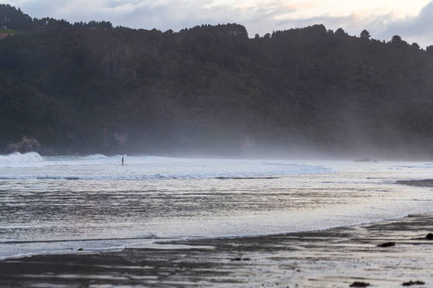 istock Man surfing the waves with a paddle board in Whangamata Beach 1547288620