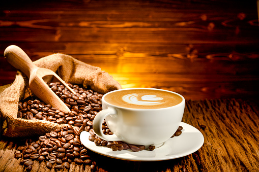 istock Cup of coffee latte and coffee beans on old wooden background 1547292732