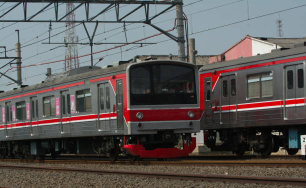 istock Commuter Train Passing by on a Railroad in Indonesia at Midday | Mass Transportation Concept 1547292995