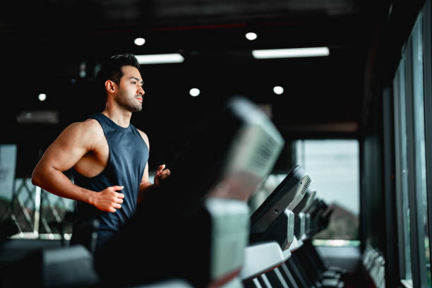 Young Asian Man Running on Treadmill - Fitness Gym Exercise Young Asian Man Running on Treadmill - Fitness Gym Exercise cardiovascular exercise stock pictures, royalty-free photos & images