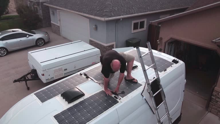 Aerial Shot of a Mature Man On Top of Camper Van Working on Solar Panels