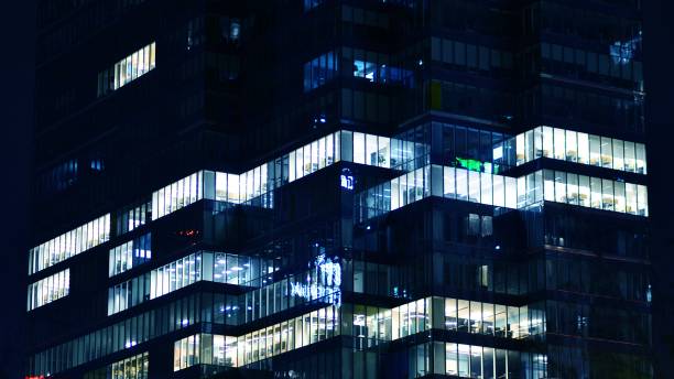 istock Pattern of office buildings windows illuminated at night. 1547357751