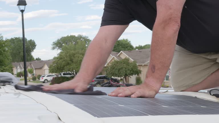 Close-Up Shot of Mature Man's Hands Cleaning Solar Panels on a Camper Van