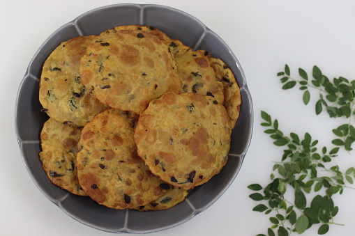 Daal poori with moringa leaves. Deep fried Indian flat bread made of whole wheat flour, cooked lentils and moringa leaves and spices. Shot on white background.