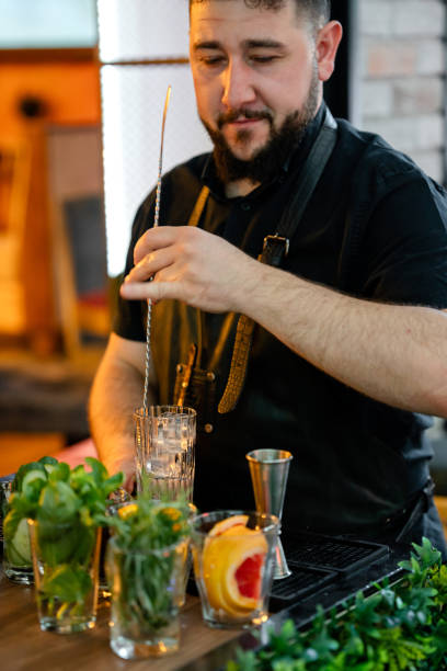 istock Smiling bartender mixing a fresh fruit cocktail in the bar 1547521576