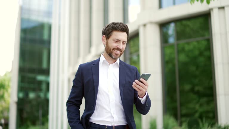 Confident mature bearded businessman in suit walking near modern business office