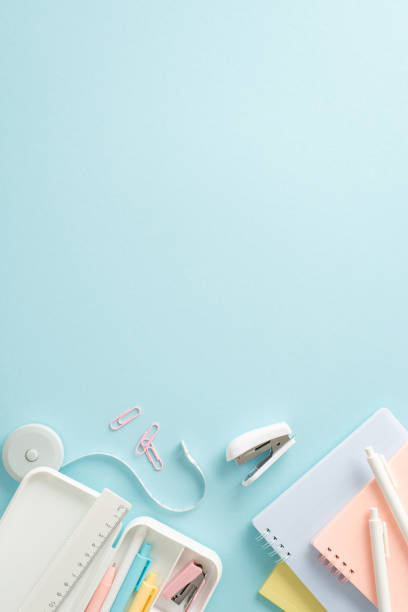 istock Fuel your educational journey with top vertical view picture displaying selection of stationery items, notepads and pencil case on blue backdrop. The empty circle allows for promotional material 1547643099