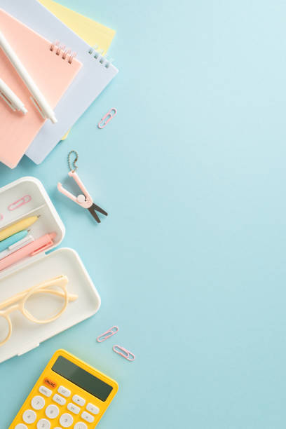 istock Unlock your full potential with top vertical view composition of impressive range of stationery essentials, notepads and calculator against blue backdrop, empty space for adding text or promotion 1547644148