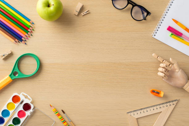 istock Educational process concept. Above view photo of empty round frame for text or advertising surrounded by album , glasses and educational equipment on wooden desk isolated background 1547652543