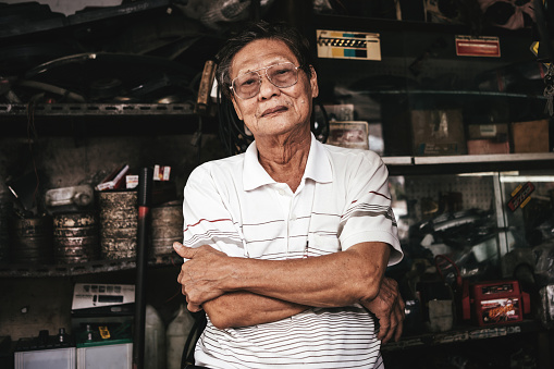 Portrait of a senior mechanic standing with arms crossed in a auto repair shop